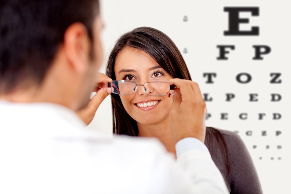 optometrist fitting glasses on woman